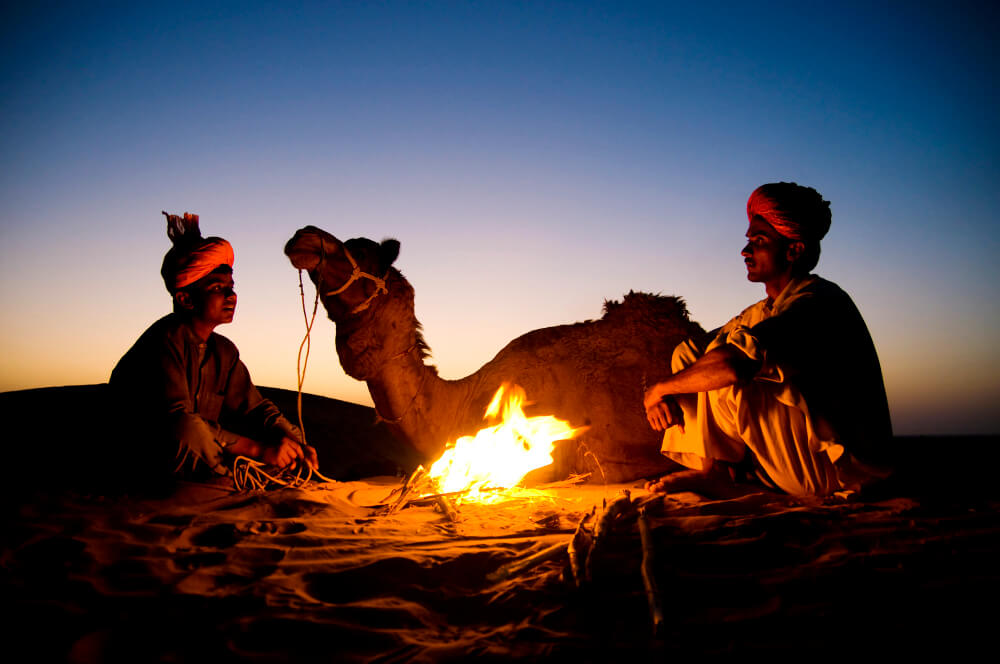 indian men resting by bonfire with their camel (1)