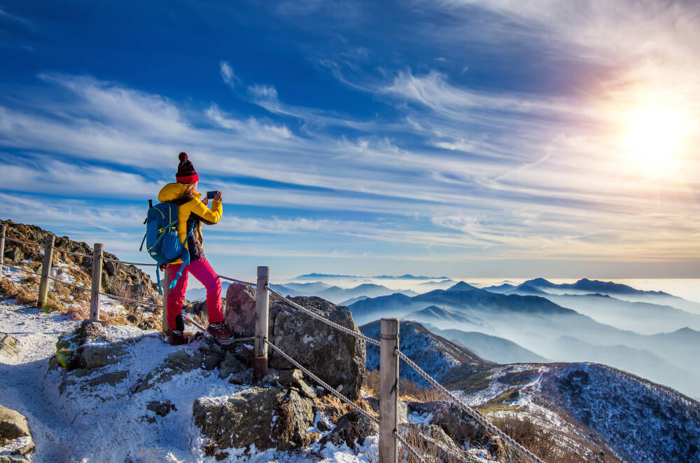 young woman hiker taking photo with smartphone mountains peak winter (1)