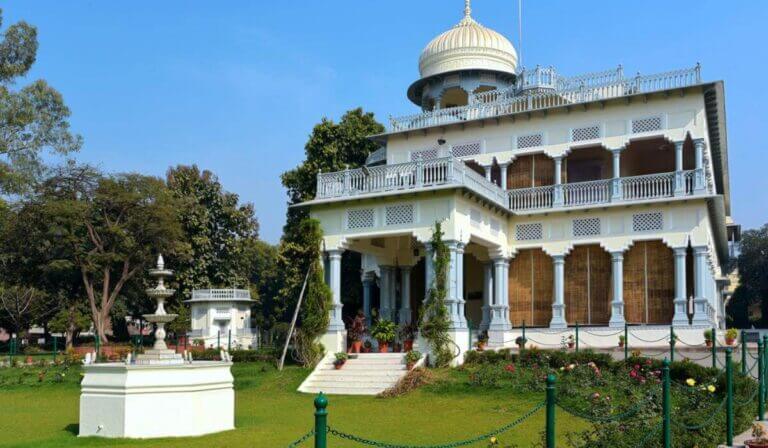Colonial-style building with verandas surrounded by a manicured garden, included in the Allahabad Tour Package.